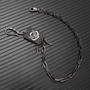Detail of punk eagle claw metal pants chain with leather patch on black background