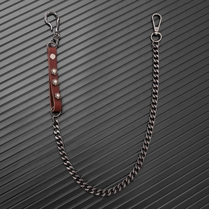Macro detail of industrial punk pants chain with skull charm, leather rivets and lobster clasp