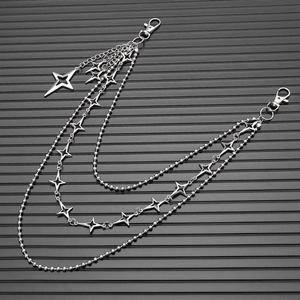 Macro detail of Y2K style multi-layer metal waist chain with hollow star charms