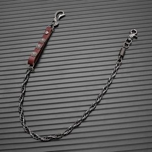 Detail of vintage punk pant chain with leather strap and decorative floral rivets