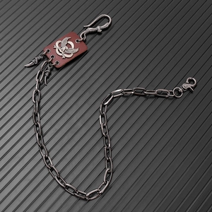 Detail of punk eagle claw waist chain with vintage leather patch and metallic pendants