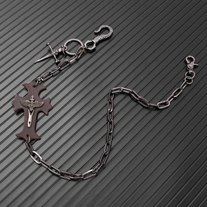 Detail of punk metal pants chain with leather cross pendant and skull dagger charm