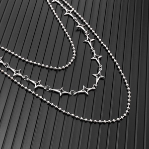 Detail of multi-layered silver star punk chain with bead link and hollow star pendants