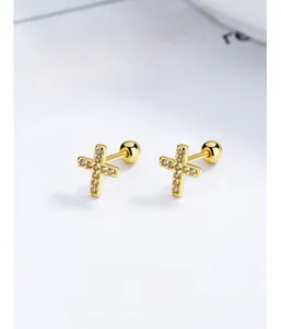 Macro shot of 925 silver cross stud earrings with sparkling cubic zirconia in gold