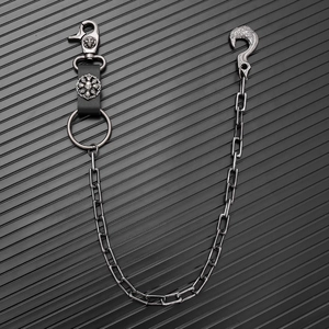 Detail of heavy metal wallet chain with skull motifs and raven hook on dark background
