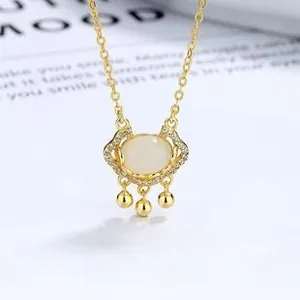 Macro view of gold peace lock necklace with white jade inlay and pavé diamonds