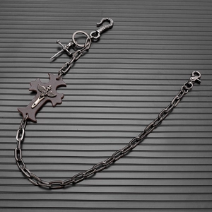 Detail of punk trousers chain with cross leather badge and skull pendant on metal link