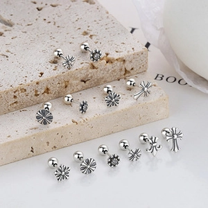 Gros plan de boucles d'oreilles rétro en argent sterling avec motifs croix et fleurs