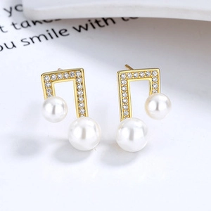 Macro shot of musical note earrings with sparkling zircons and elegant white pearls