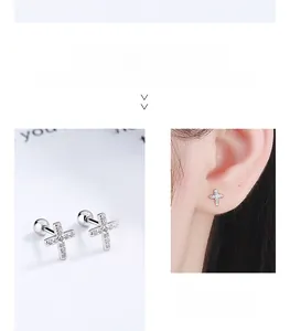 Macro detail and on-ear look of S925 sterling silver cross studs with zircon stones