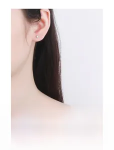 Close-up of a minimalist silver barbell screw back stud earring on a model's ear