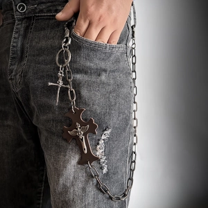 Gothic punk metal waist chain with engraved cross and sword pendants on grey jeans