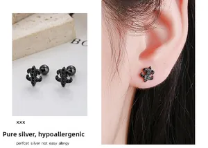 Détail macro de boucles d'oreilles fleur de lys noires avec fermoir à vis sécurisé