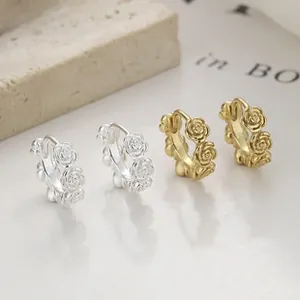 Detail of 925 silver and gold rose flower hoop earrings on an elegant marble base