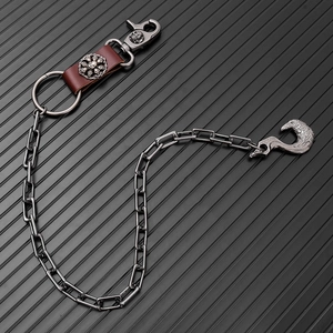 Detail of punk trousers chain featuring skull clasp, leather accent, and eagle head hook
