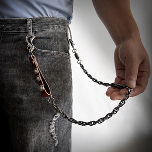 Detail of dark punk trousers chain with vintage leather strap and sunflower metal buckles