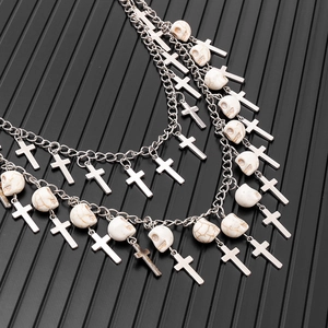 Detail of hip-hop multi-layer silver pants chain with cross and skull charms on black background