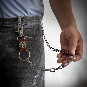 Detail of punk style waist chain with leather accents and skull metal clasp on jeans