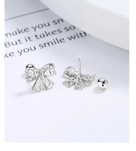 Macro view of hollow bow-shaped sterling silver stud earrings with heart patterns