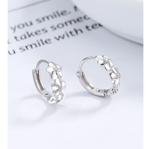 Close-up of S925 sterling silver flower earrings with white zircon centers on a white desk