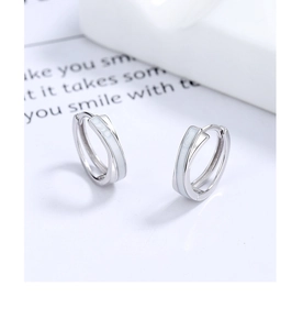 Vue détaillée de boucles d'oreilles créoles en argent 925 avec incrustation d'émail blanc