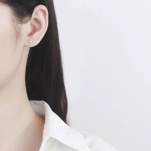 Minimalist 925 sterling silver cross stud earring with cubic zirconia on female model
