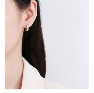 Gros plan de boucles d'oreilles en émail or et blanc portées par un mannequin femme