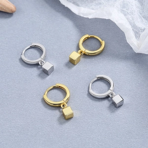 Detail view of gold and silver geometric cube drop earrings with sleek mirror finish