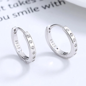 Close-up of S925 sterling silver hollow heart hoop earrings with white zircon accents