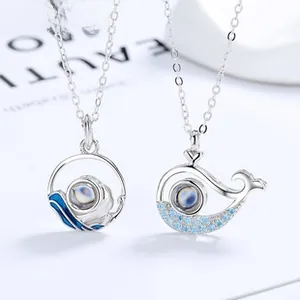 Detail of silver Mobius couple necklaces with wave pattern and whale projection stone