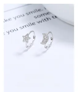 Vue détaillée des boucles d'oreilles asymétriques en argent avec étoile, lune et zircons