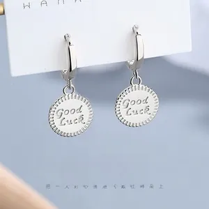 Detail of 925 sterling silver hoop earrings with a Good Luck engraved round charm