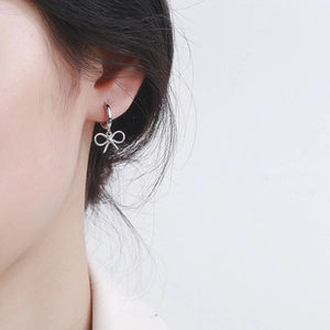 Close-up of 925 sterling silver bow knot hoop earrings worn on a female ear model