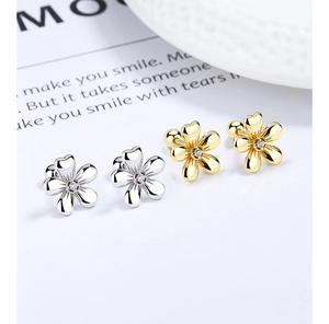 Detailed macro of flower stud earrings in gold and silver with cubic zirconia
