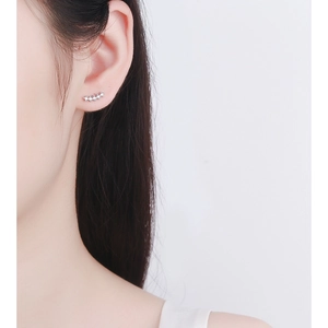 Close-up of minimalist silver curved bar earrings with five sparkling white zircons on ear