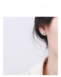 Close-up of polished 925 sterling silver flower stud earring with central diamond on ear