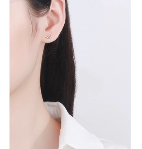 Macro view of minimalist sterling silver angel wing stud earrings on model's ear