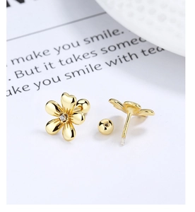 Macro detail of gold flower studs with zircon center and secure screw-back ball closures