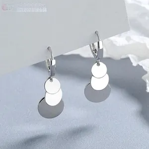 Détail de boucles d'oreilles argentées à trois disques superposés sur carte de présentation