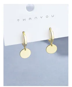 Macro shot of polished gold round earrings with smooth disc charms on display card