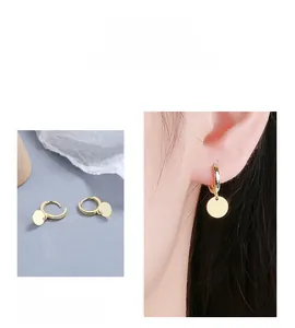 Detail of 925 sterling silver gold plated hoop earrings with minimalist round disc charms