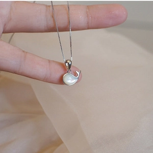 Detailed view of a silver whale pendant with shell inlay on a delicate chain