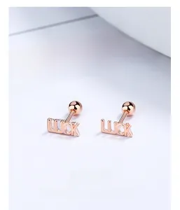 Macro shot of rose gold LUCK letter stud earrings with secure screw-on ball backings