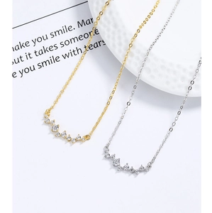 Macro detail of gold and silver curved zircon pendant necklaces on a ceramic plate