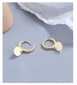 Macro detail of gold S925 sterling silver hoop earrings with polished disc pendants