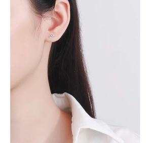 Close-up of minimalist S925 sterling silver Luck letter stud earring worn by a model