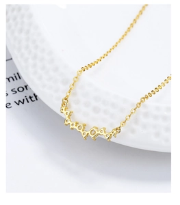 Macro view of gold smile necklace with zircon detail on white embossed ceramic plate