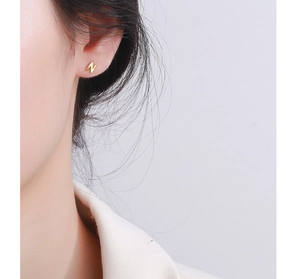 Macro shot of minimalist gold letter N stud earring on model for daily style