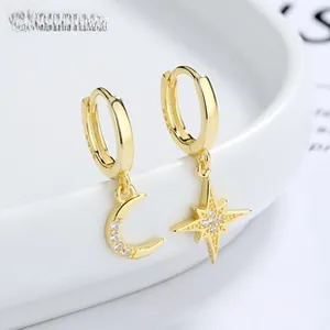 Detail of 925 sterling silver gold hoop earrings with asymmetric star and moon charms