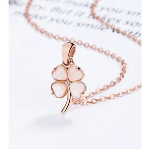 Close-up of rose gold four-leaf clover pendant with pink opal and tiny crystal detail
